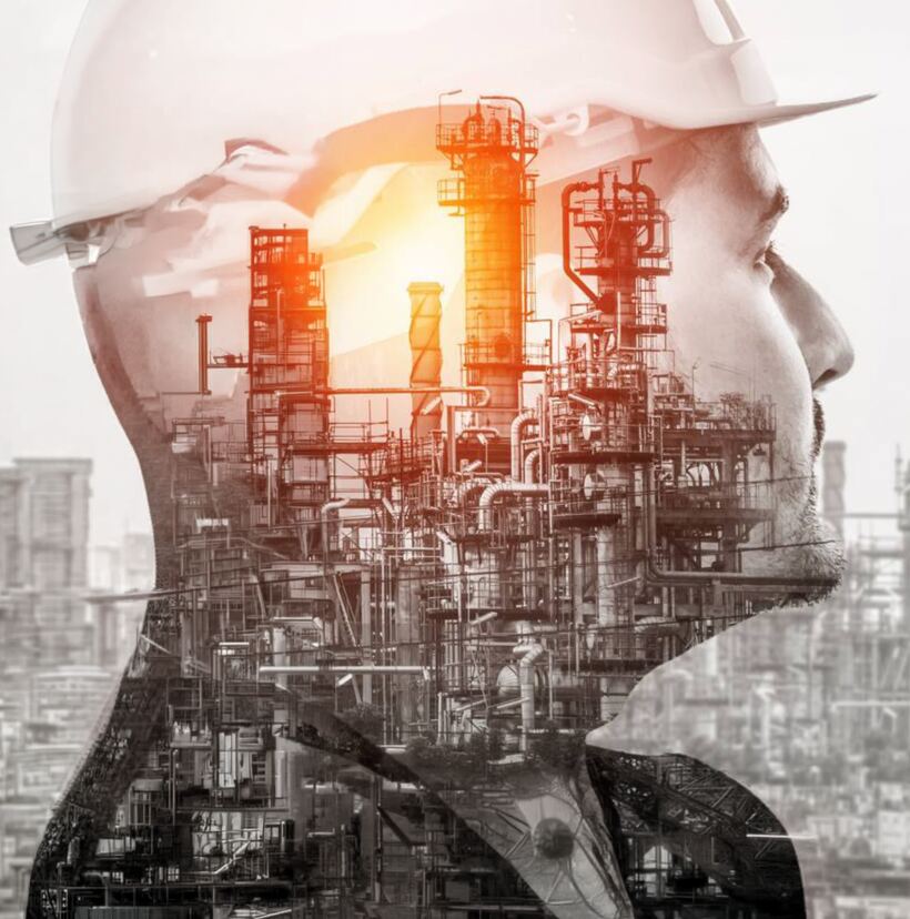 Double-exposure image of an engineer in a hard hat overlaid with an industrial processing plant