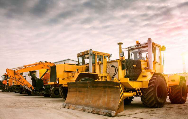 Yellow earthmoving equipment, including a bulldozer and excavators, parked on a site